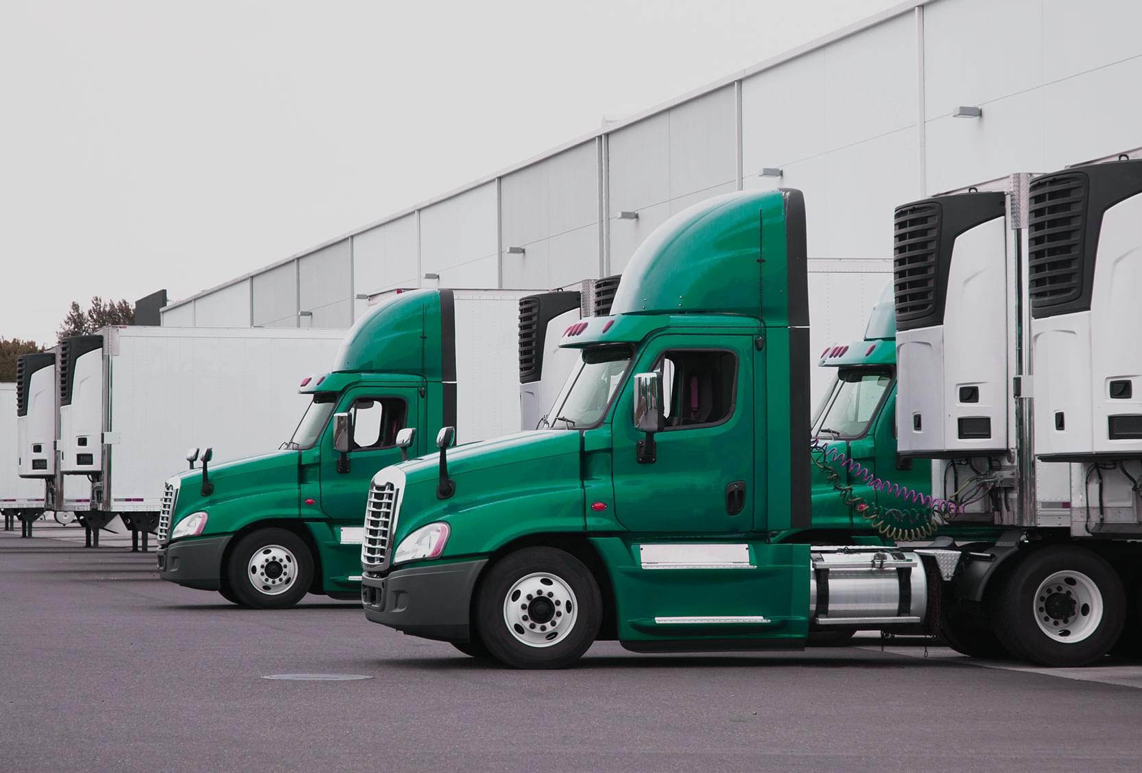 Multiple trucks and trailers backed into a crossdocking, warehousing facility for third party logistics service.